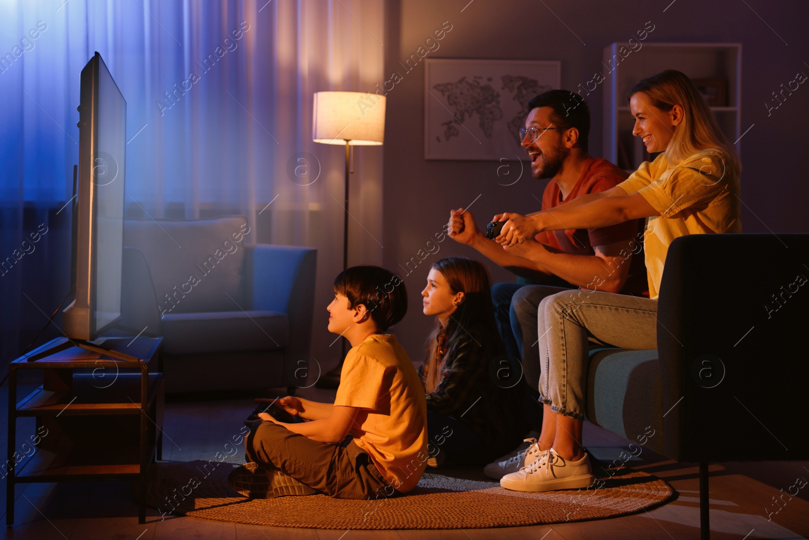 Photo of Happy family playing video games in living room at night