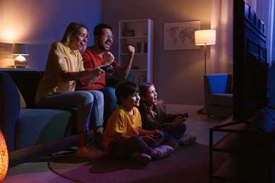 Photo of Happy family playing video games in living room at night