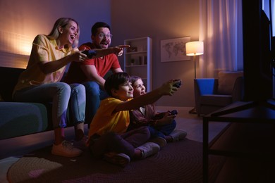 Photo of Happy family playing video games in living room at night