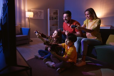 Photo of Happy family playing video games in living room at night