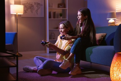 Photo of Happy mother and her daughter playing video games at home