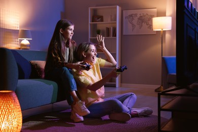 Photo of Happy mother and her daughter playing video games at home