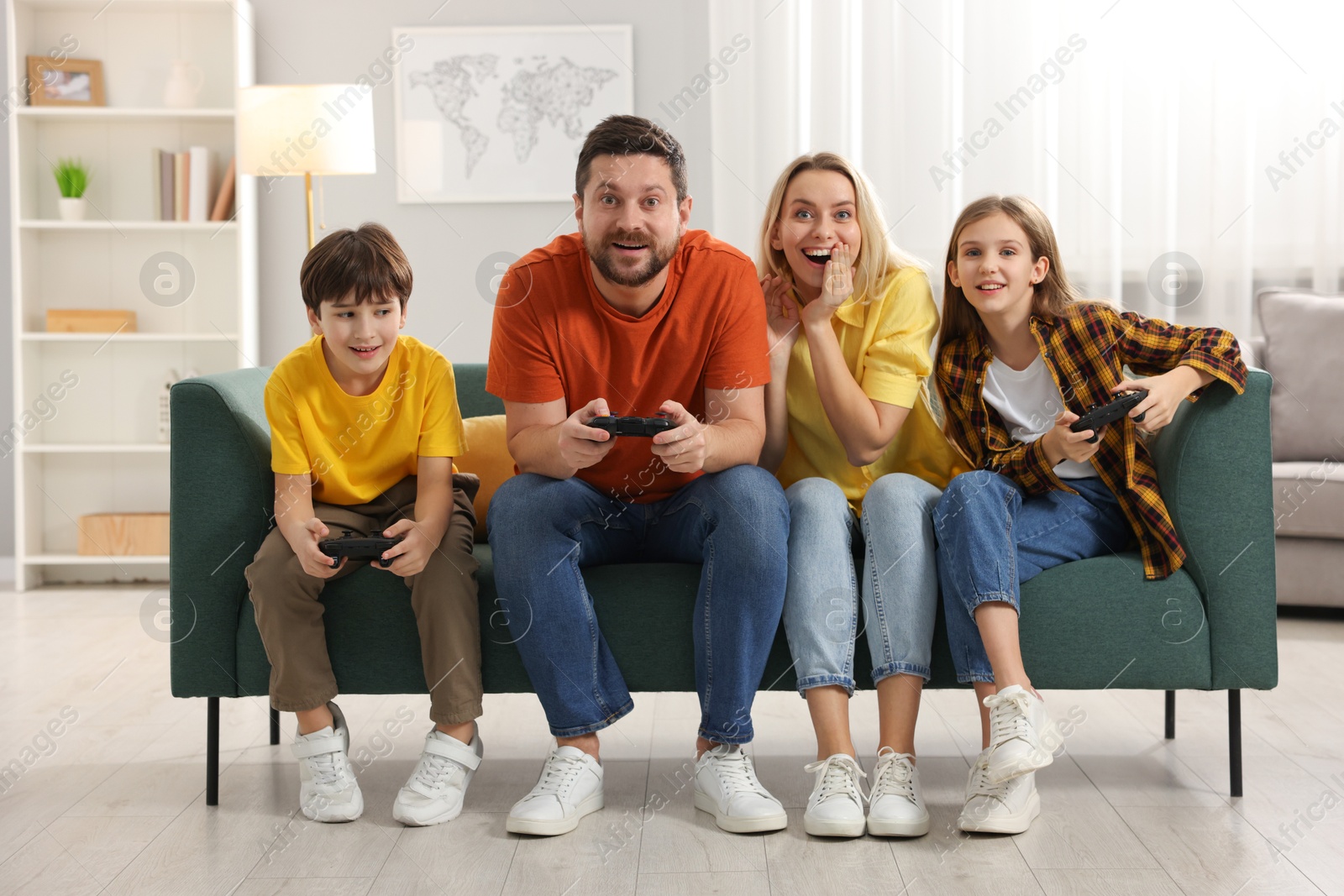 Photo of Happy family playing video games on sofa in living room