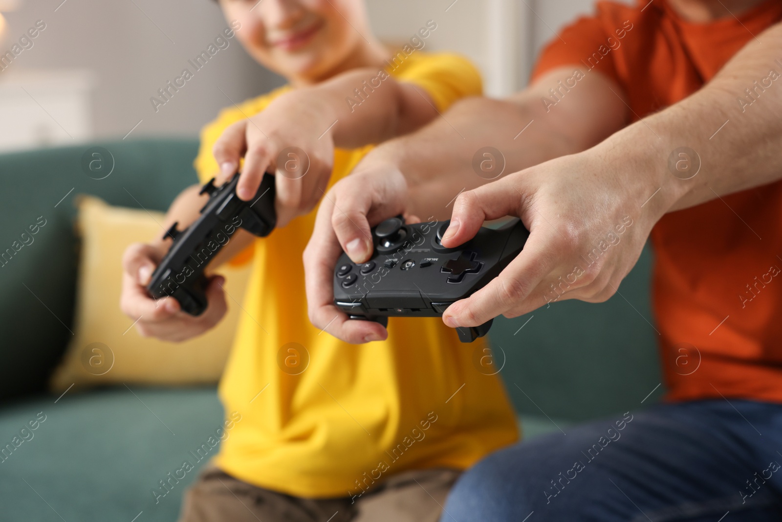 Photo of Father and his son playing video games at home, closeup