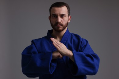 Photo of Karate fighter in uniform on grey background