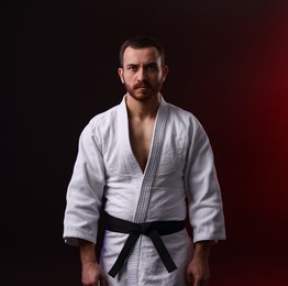 Photo of Karate fighter wearing uniform in color light against black background