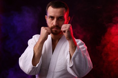 Photo of Karate fighter in color lights and smoke against black background