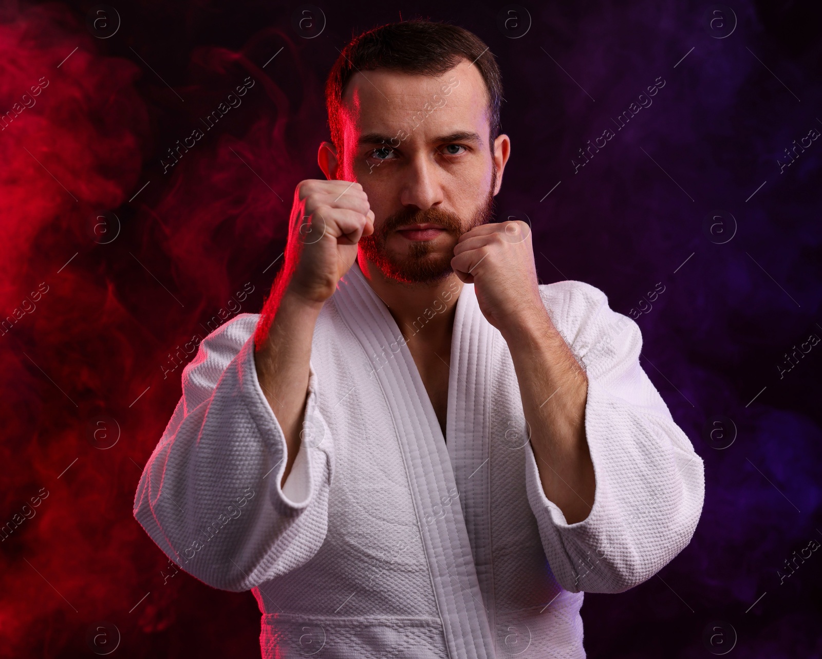 Photo of Karate fighter in color lights and smoke against black background