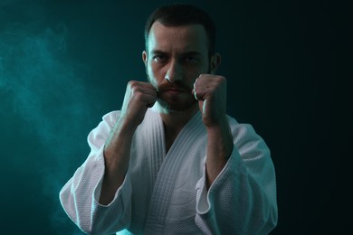 Photo of Karate fighter wearing uniform in color lights and smoke