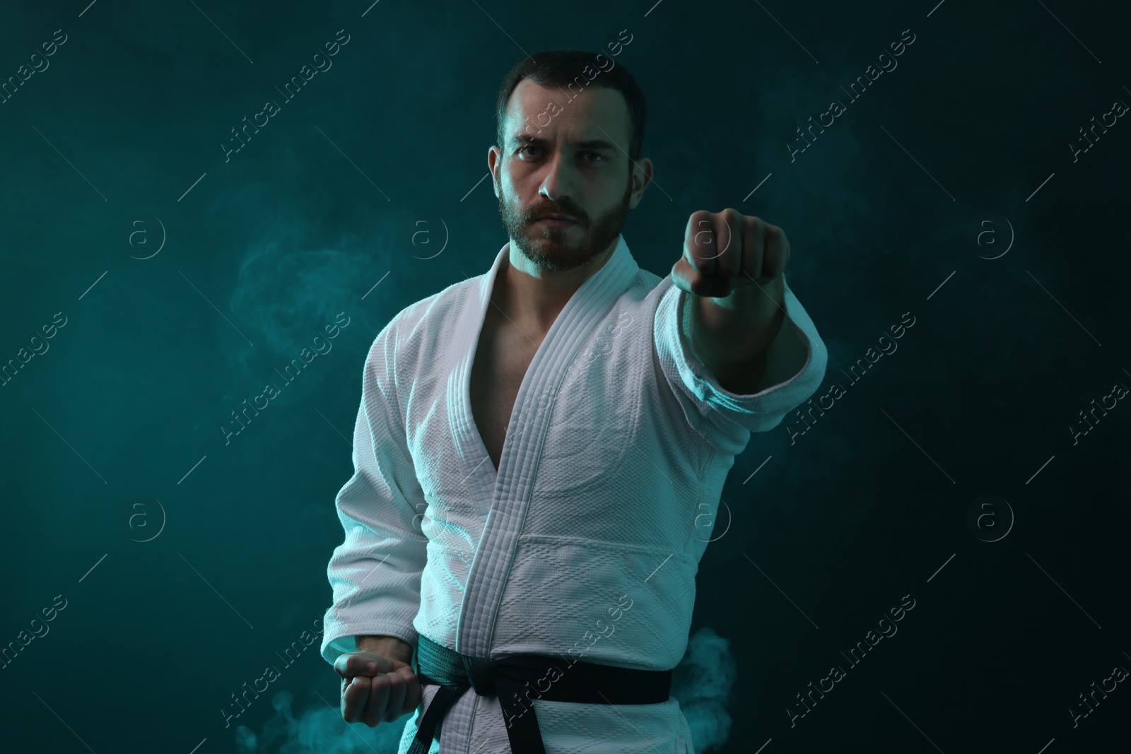 Photo of Karate fighter wearing uniform in color lights and smoke