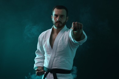 Photo of Karate fighter wearing uniform in color lights and smoke