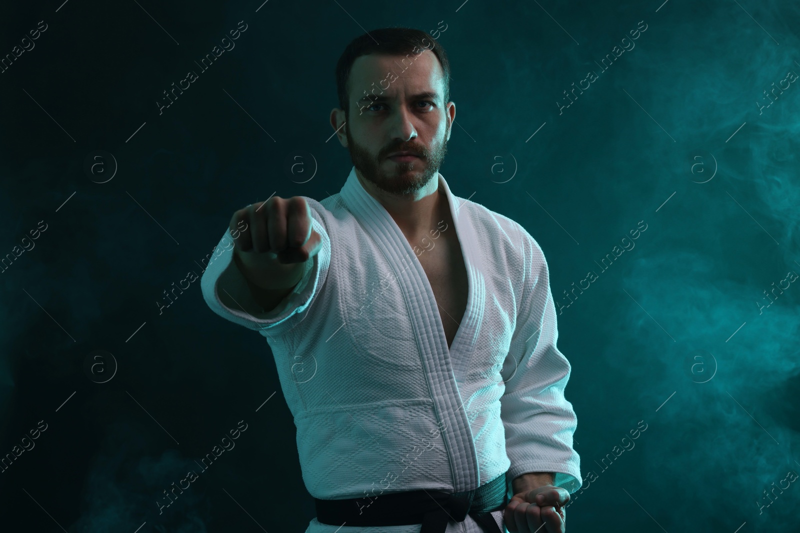 Photo of Karate fighter wearing uniform in color lights and smoke