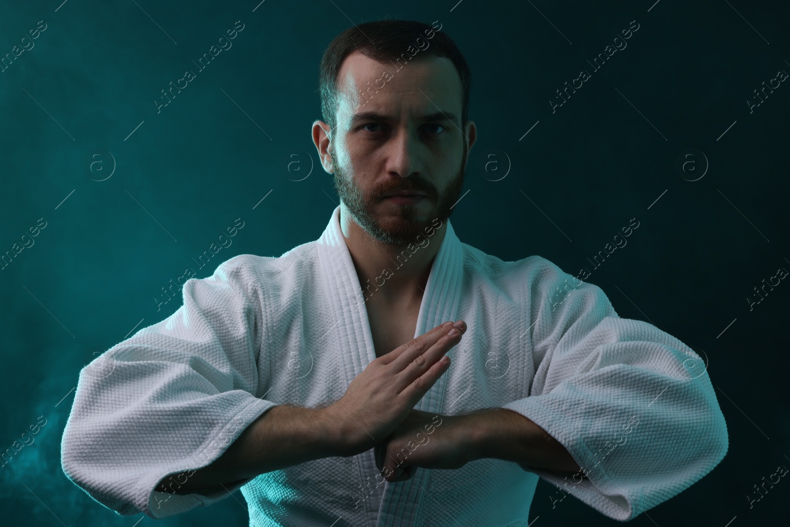 Photo of Karate fighter wearing uniform in color lights and smoke