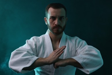 Photo of Karate fighter wearing uniform in color lights and smoke