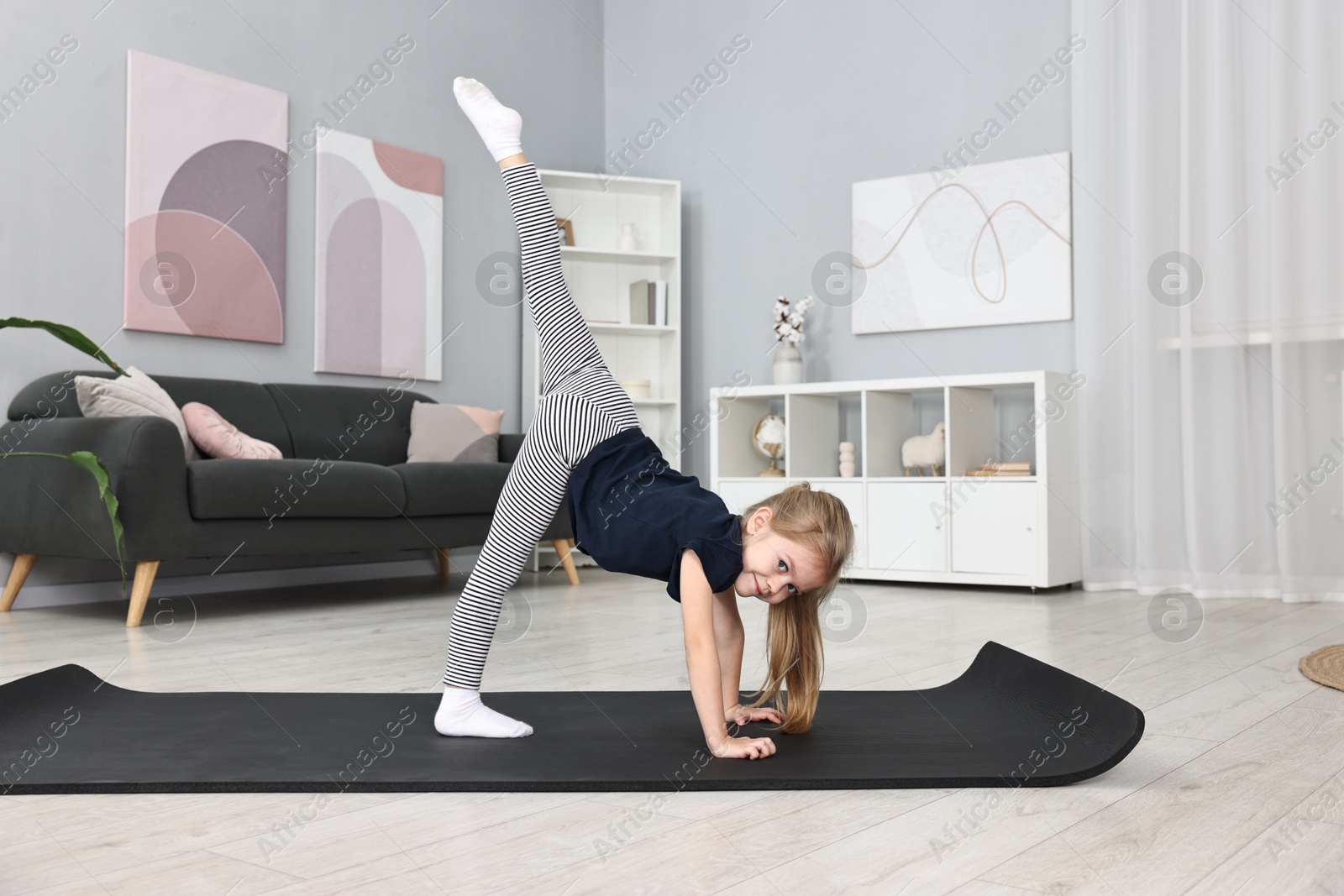 Photo of Little girl exercising on fitness mat at home. Sport activity