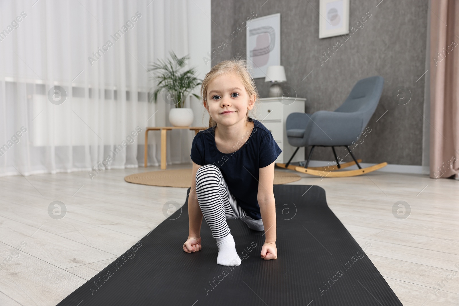 Photo of Little girl exercising on fitness mat at home. Sport activity