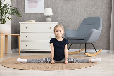 Photo of Little girl exercising on rug at home. Sport activity