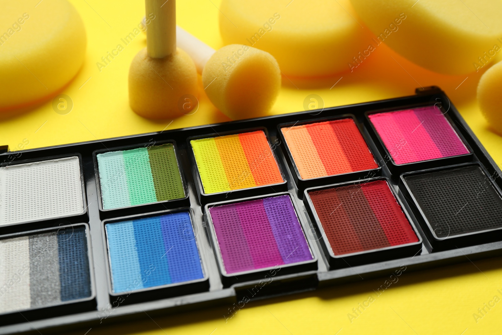 Photo of Face paints and tools on yellow background, closeup