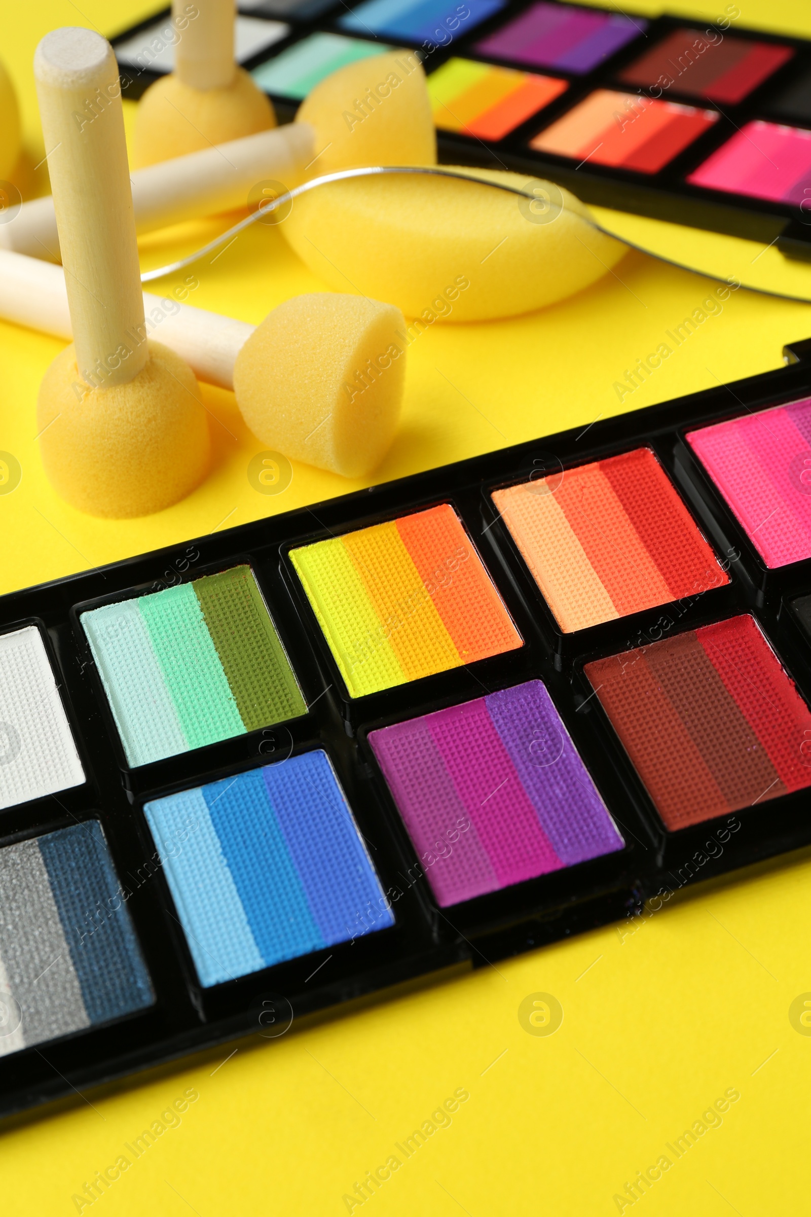 Photo of Face paints and tools on yellow background, closeup