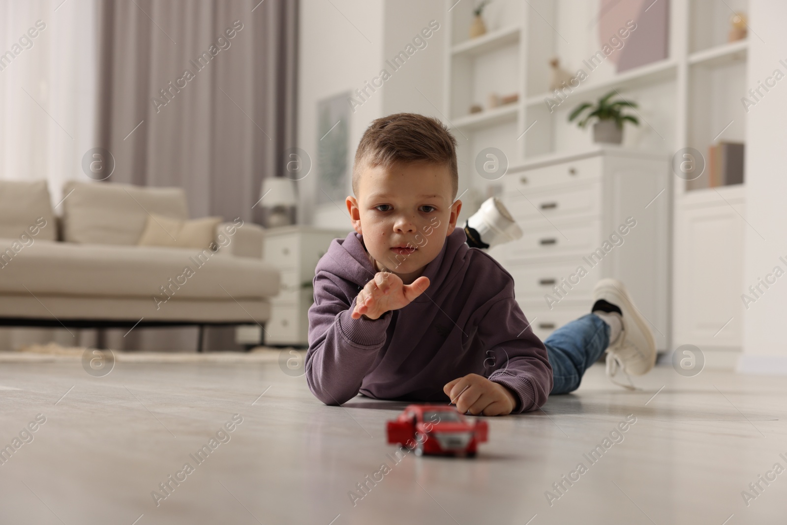 Photo of Little boy playing with toy car at home