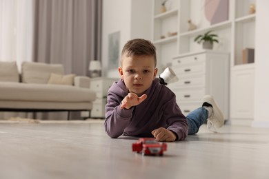 Photo of Little boy playing with toy car at home