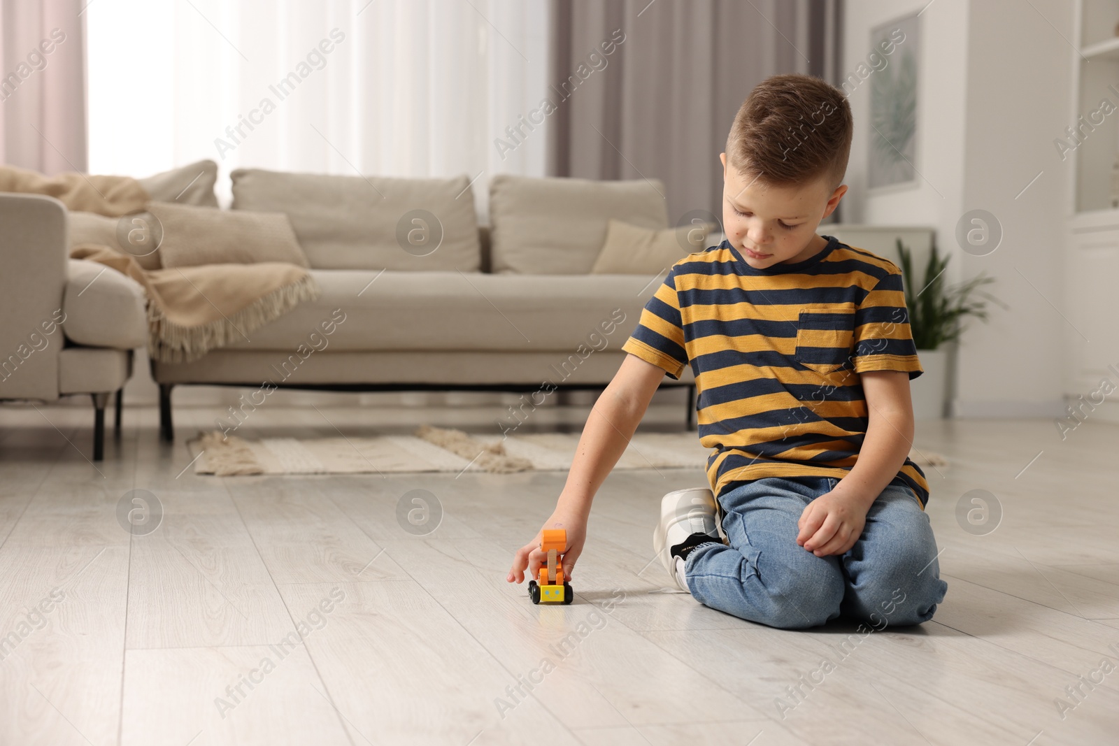 Photo of Little boy playing with toy car at home. Space for text