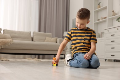 Photo of Little boy playing with toy car at home. Space for text