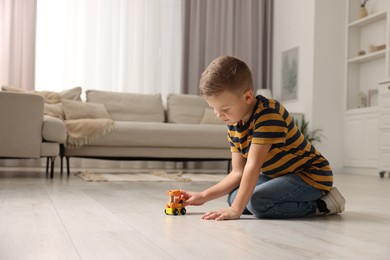 Photo of Little boy playing with toy car at home. Space for text