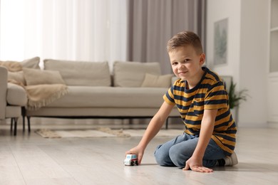 Photo of Little boy playing with toy car at home. Space for text