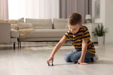 Photo of Little boy playing with toy car at home. Space for text