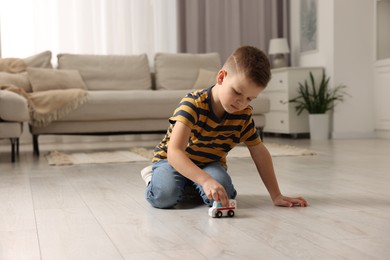 Photo of Little boy playing with toy car at home. Space for text