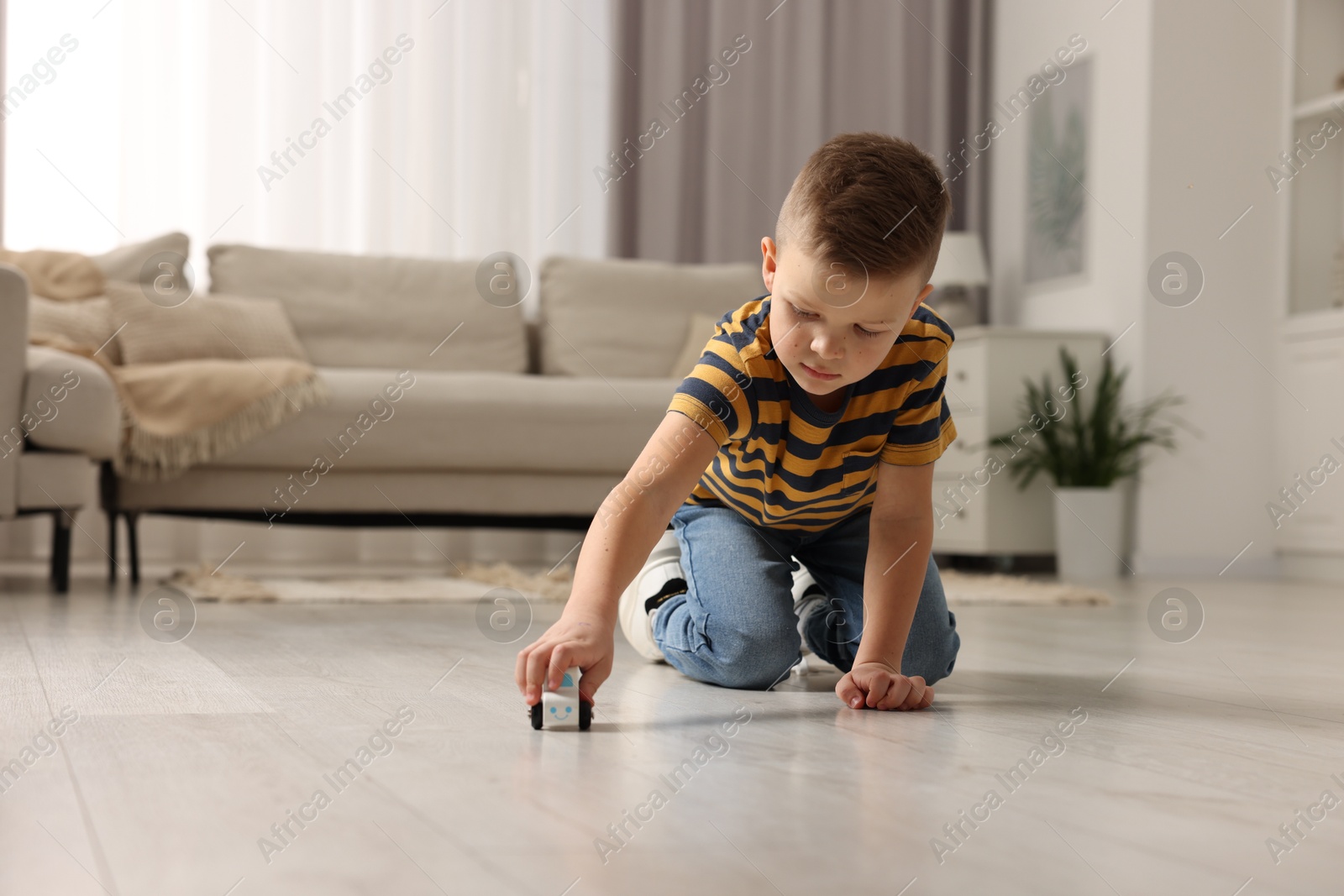 Photo of Little boy playing with toy car at home. Space for text