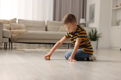 Photo of Little boy playing with toy car at home. Space for text