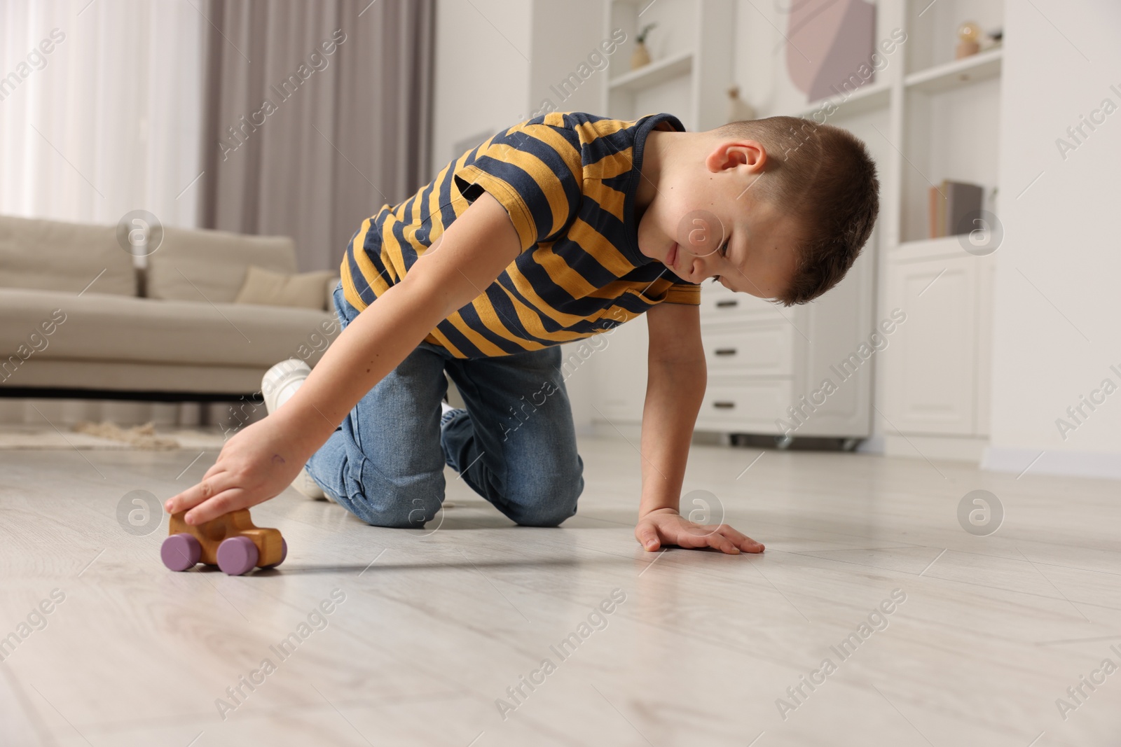 Photo of Little boy playing with toy car at home