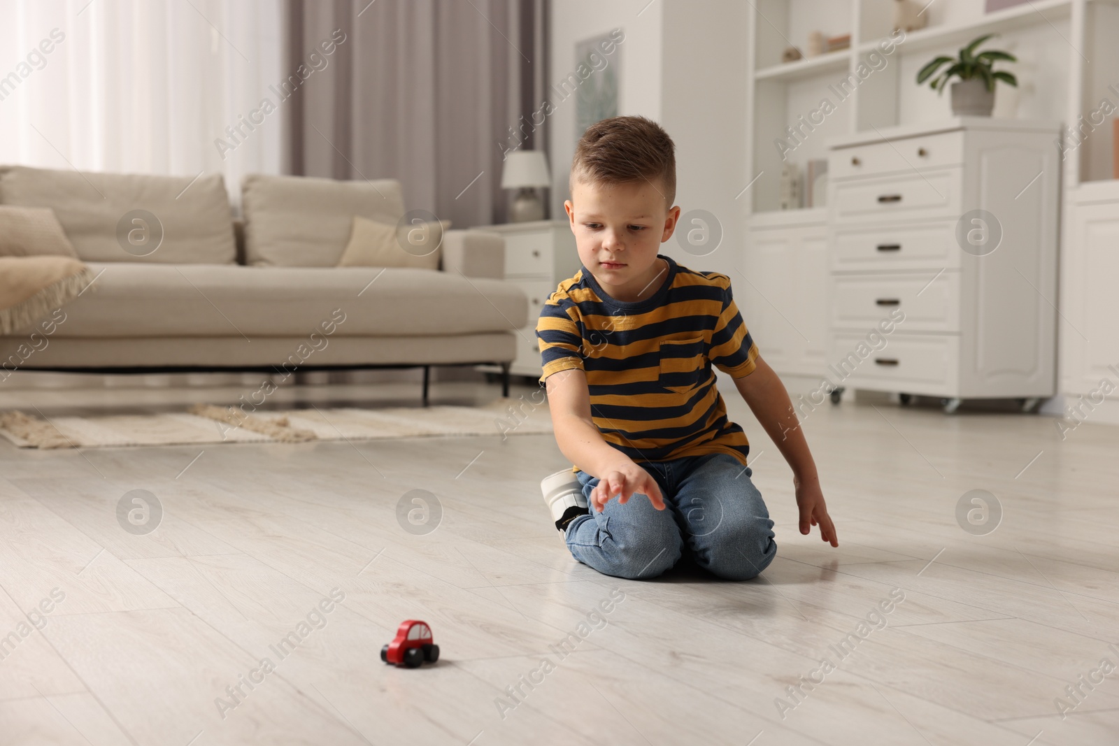 Photo of Little boy playing with toy car at home. Space for text