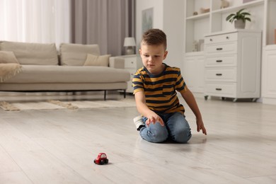 Photo of Little boy playing with toy car at home. Space for text