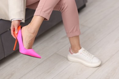 Photo of Woman changing shoes on sofa indoors, closeup