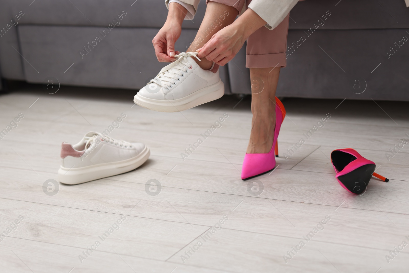 Photo of Woman changing shoes on sofa indoors, closeup