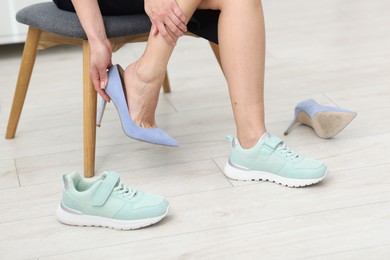 Photo of Woman changing shoes on chair indoors, closeup