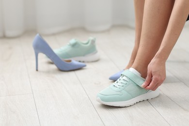 Photo of Woman changing into sneakers indoors, closeup view