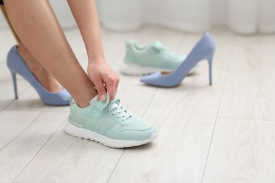 Photo of Woman changing into sneakers indoors, closeup view