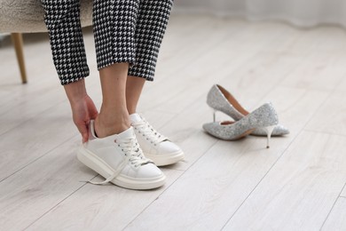 Photo of Woman changing shoes in armchair indoors, closeup