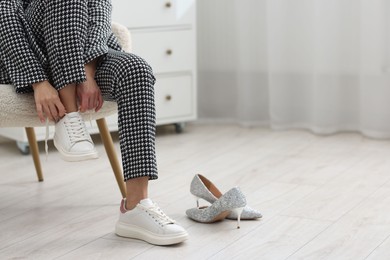 Photo of Woman changing shoes in armchair indoors, closeup. Space for text