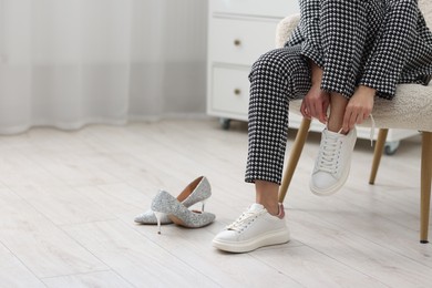 Photo of Woman changing shoes in armchair indoors, closeup. Space for text