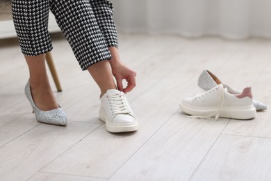 Photo of Woman changing shoes on chair indoors, closeup