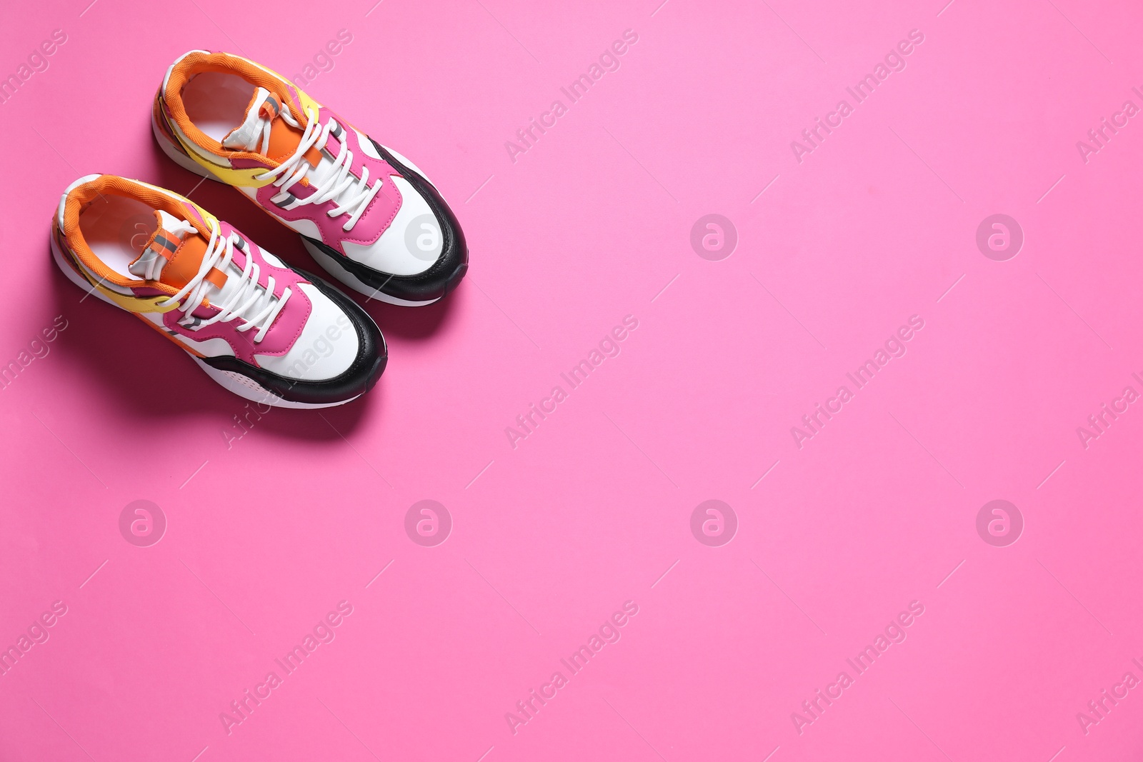 Photo of Sportive shoes. Pair of stylish sneakers on pink background, flat lay. Space for text