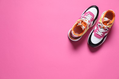 Photo of Sportive shoes. Pair of stylish sneakers on pink background, flat lay. Space for text