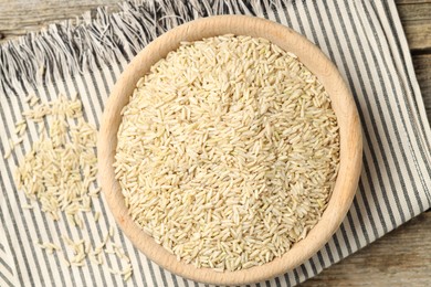 Photo of Brown rice in bowl on wooden table, top view