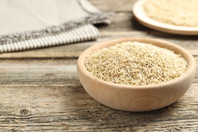 Photo of Brown rice in bowl on wooden table, closeup. Space for text