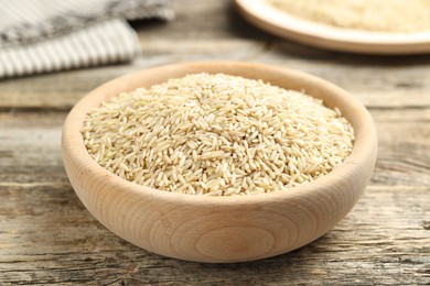 Photo of Brown rice in bowl on wooden table, closeup